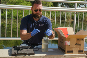 man sampling water by a pond